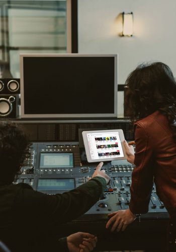 sound producers using tablet together at recording studio with youtube website on screen